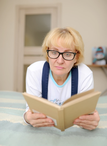La mujer con gafas lee el libro
 - Foto, Imagen