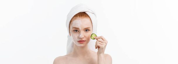 Attractive Young Woman with beautiful clean skin. White mask and cucumbers. Beauty treatments and cosmetology spa therapy. White background. - Photo, Image