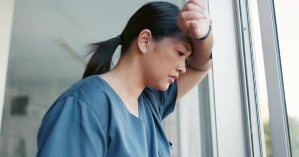 Healthcare nurse, stress and headache by window for working burnout, frustrated employee and tired asian woman in hospital. Doctor, pain and sad medical worker, anxiety or mental health depression. - Footage, Video