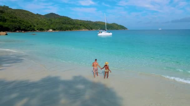 Pareja en la playa de Anse Lazio en la isla de Praslin Seychelles, hombres y mujeres en un océano azul turquesa - Imágenes, Vídeo
