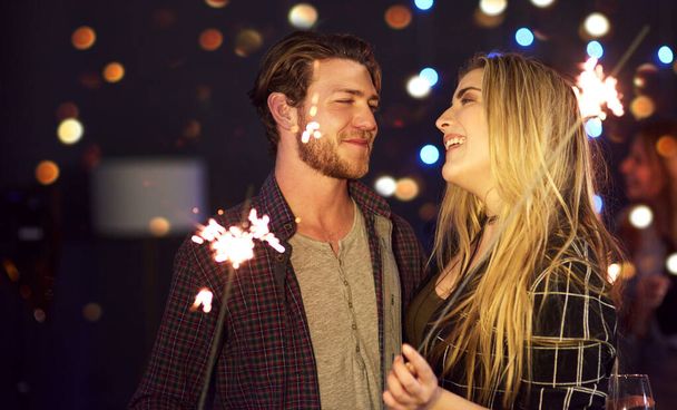 Ela é o verdadeiro brilho da minha vida. um atraente jovem casal se divertindo com sparklers em uma boate - Foto, Imagem