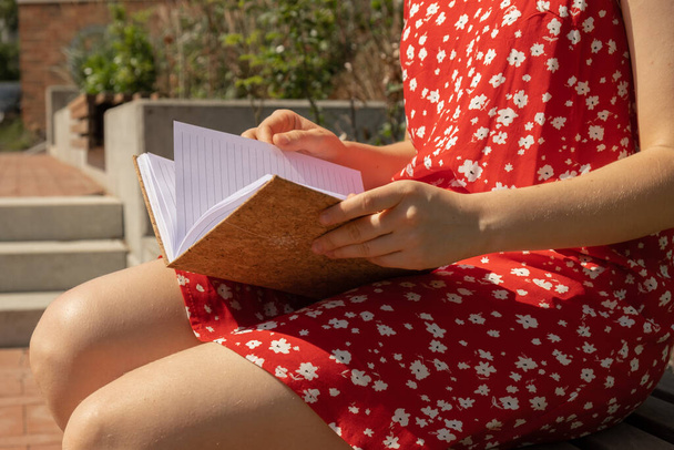 Unrecognizable Young woman in red dress Writing Gratitude Journal on wooden bench. Today I am grateful for. Self discovery journal, self reflection creative writing, self growth personal development concept. Self care wellbeing spiritual health, bein - Photo, Image