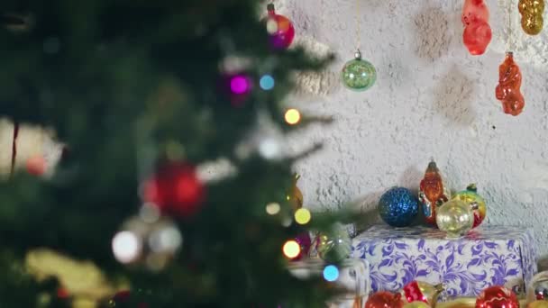 Glazen bal met ruitjes hangend aan een tak op nieuwjaarsavond. Vintage speelgoed op de kerstboom. Close-up decoratie voor een feestelijke avond. Gekleurde lichten flikkeren op de achtergrond. - Video