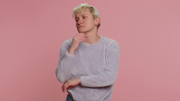 Thoughtful clever millennial woman with short hair rubbing chin and looking aside with pensive expression, pondering a solution, doubting question. Young girl on pink background. Lgbt lesbian people - Footage, Video