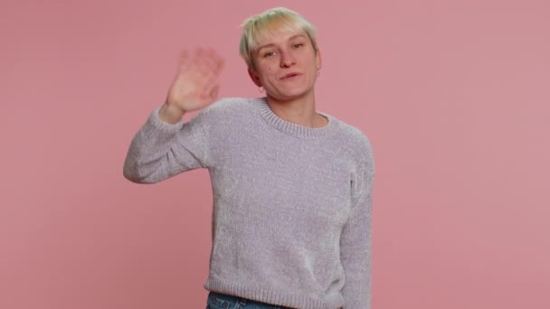 Come here, join us. Welcome. Lovely millennial woman showing inviting gesture with hands, ask to join, beckoning to coming, gesturing hello or goodbye. Girl on pink background. Lgbt gay lesbian people - Footage, Video