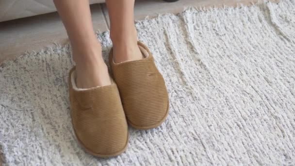 Les femmes pieds portent des pantoufles chaudes sur le tapis près du lit le matin. - Séquence, vidéo