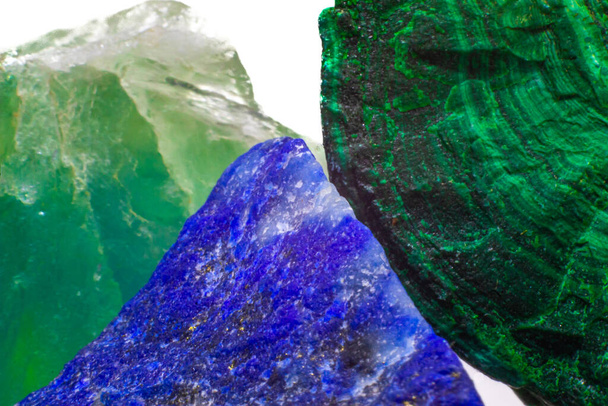 Raw close up focused vibrant green malachite with dark green bands, deep blue lapis lazuli with gold pyrite and a light green to blue raw fluorite crystal stone isolated on a white surface backround - Fotoğraf, Görsel