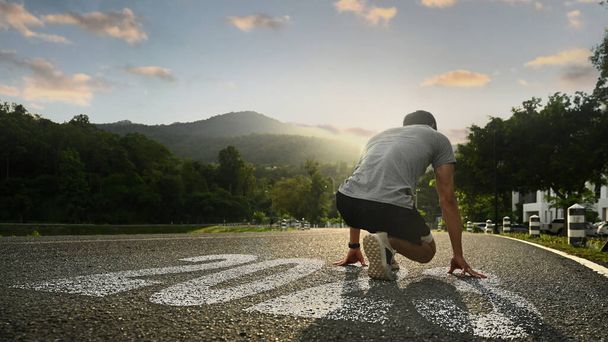 Sport man in startpositie met prachtige zonsondergang op de achtergrond. Nieuwe uitdaging, doelstellingen, begin en begin van het nieuwe jaar 2023. - Foto, afbeelding