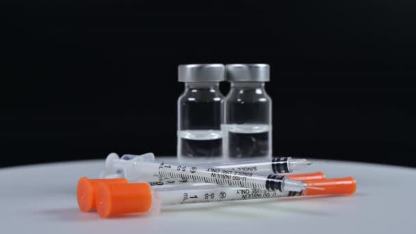 Inzulinové injekční stříkačky a injekční lahvičky na rotujícím bílém pozadí - Záběry, video