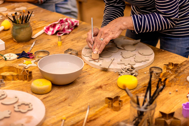 Керамическая мастерская. Пожилая женщина, работающая с керамикой. - Фото, изображение