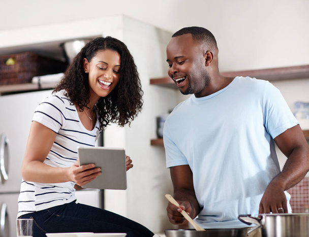 Há algumas receitas loucas online. um jovem casal usando um tablet enquanto cozinham juntos na cozinha em casa - Foto, Imagem
