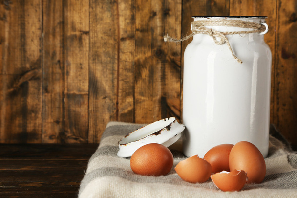 Milk can with eggs and eggshell on rustic wooden background - Zdjęcie, obraz