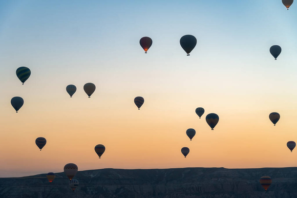 カッパドキアの美しい日の出を背景に飛行する気球。夏休みに人気の観光地 - 写真・画像