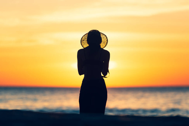 mooie vrouwen zijn eenzaam op vakantie aan de oceaan tijdens zonsondergang op de zee wazig achtergrondsilhouet stijl - Foto, afbeelding