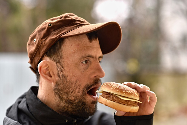 Mann isst einen Hamburger - Foto, Bild
