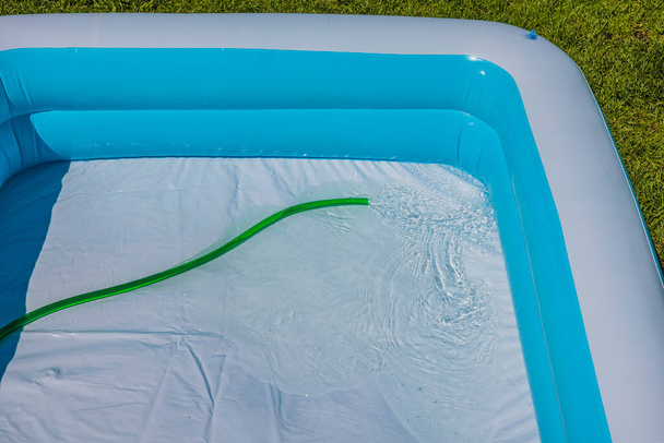 Крупним планом дитячий басейн наповнений водою з садового шланга
. - Фото, зображення