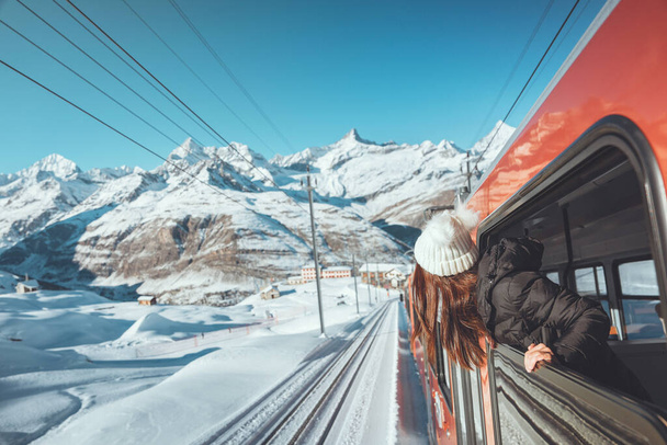 Щаслива жінка мандрівник дивиться з вікна, подорожуючи поїздом в красивих зимових горах, концепція подорожей
. - Фото, зображення