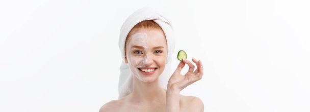 Vonzó fiatal nő szép tiszta bőr. Fehér maszkot, és uborka. Kozmetikai kezelések és kozmetológiai spa kezelés. Fehér háttér. - Fotó, kép