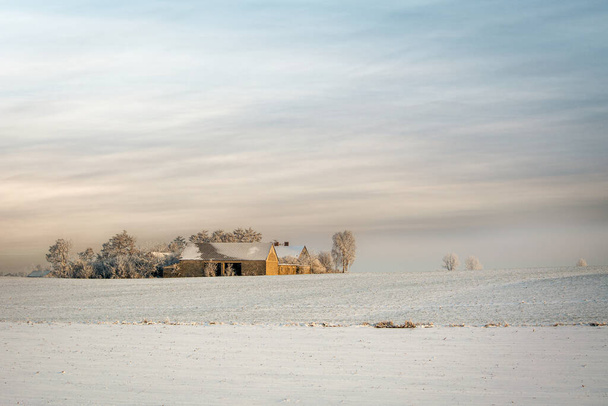 Зимний пейзаж с одиноким домом на заднем плане. - Фото, изображение