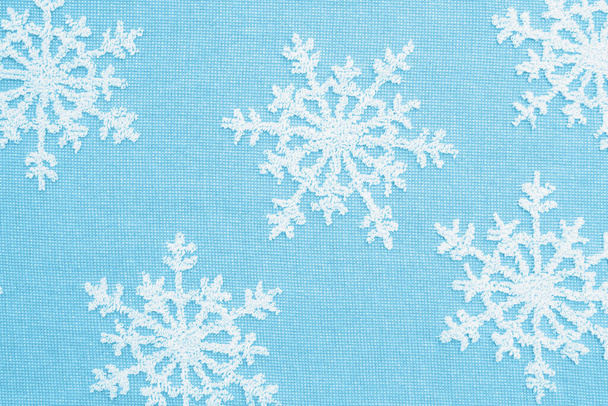 White snowflakes on blue ay material holiday background for your winter or seasonal message - Photo, Image