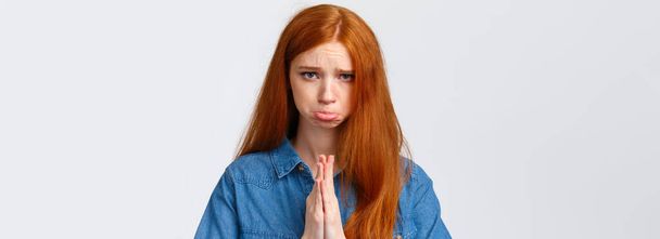 Pretty please. Close-up portrait sad, sulking cute redhead girl feeling guilty begging apology, pouting and frowning hopeful look camera, press hands together in pray, pleading over white background. - Photo, Image