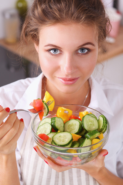 Mujer joven comiendo ensalada fresca en la cocina moderna - Foto, imagen