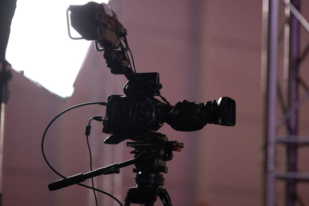 Schwarze Filmkamera und Licht hinter den Kulissen der Spielemesse. Mittelschuss - Foto, Bild