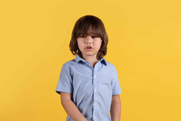 Kindertraurigkeit. Studioporträt eines aufgebrachten kleinen Jungen, der kurz vor dem Weinen steht, sich unglücklich und beleidigt fühlt, orangefarbener Hintergrund, freier Raum - Foto, Bild