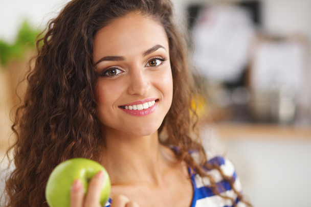 Happy young woman eating apples on kitchen - Фото, зображення