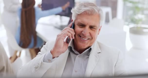 Oficina, corporativo y hombre de negocios senior en una llamada telefónica mientras que un teléfono celular mientras que trabaja en una computadora. Gerente de tecnología, profesionales y ancianos en una conversación móvil en un espacio de coworking - Imágenes, Vídeo