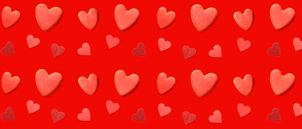 Many tasty cookies in shape of hearts on red background. Pattern for Valentine's Day - Photo, Image