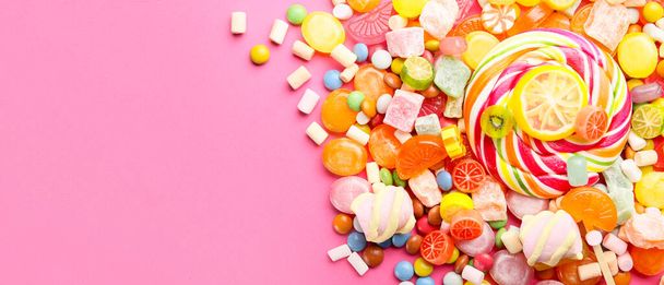 Ассортимент сладких конфет на розовом фоне с пространством для текста - Фото, изображение