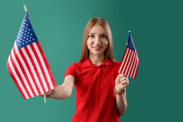 Yeşil arka planda ABD bayrakları olan genç kızıl saçlı kadın. - Fotoğraf, Görsel