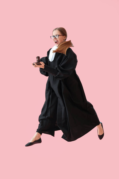 Злая женщина-судья с молотком прыгает на розовом фоне - Фото, изображение