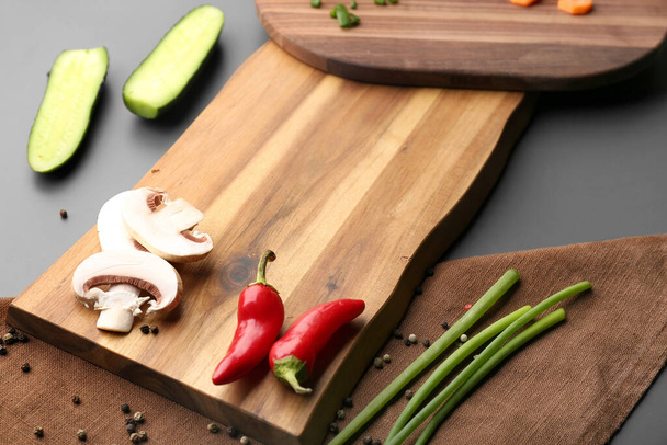 Wooden cutting board and fresh vegetables on grey background - Photo, Image