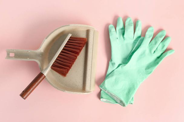 Dustpan com escova de limpeza e luvas de borracha sobre fundo rosa - Foto, Imagem