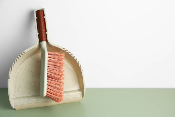 Dustpan and cleaning brush on color floor near light wall - Photo, Image