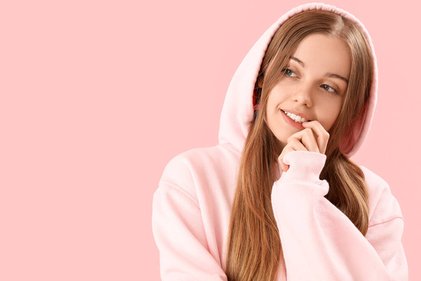 Junge Frau im Kapuzenpulli beißt Nägel auf rosa Hintergrund, Nahaufnahme - Foto, Bild