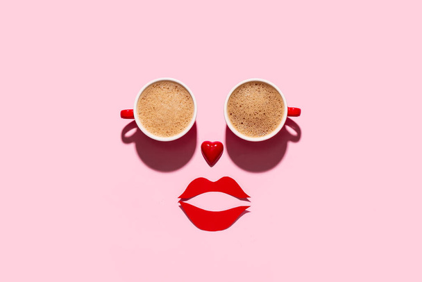 Rosto feito de xícaras de café, coração e lábios de papel no fundo rosa. Celebração do Dia dos Namorados - Foto, Imagem