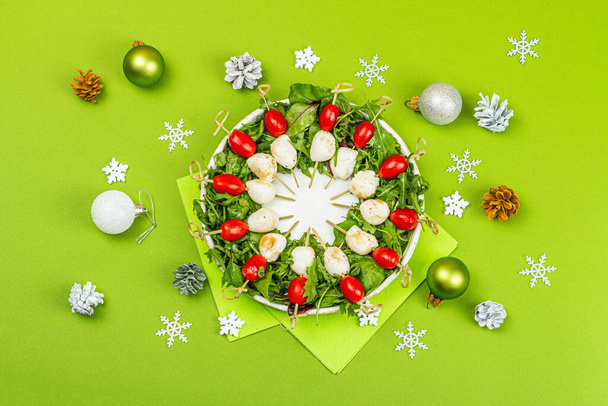Charcuterie krans in traditionele Nieuwjaar kleur ontwerp met kerstversiering. Moderne snack, matte groene achtergrond, vlakke lay, bovenaanzicht - Foto, afbeelding