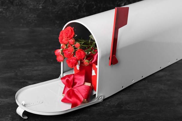Postaláda ajándékokkal és rózsákkal sötét háttérrel. Valentin-napi ünneplés - Fotó, kép
