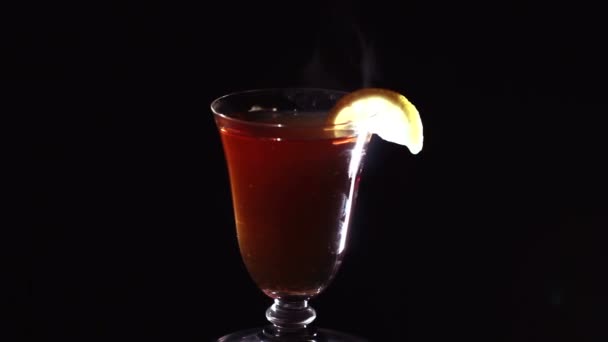 Ποτήρι ζεστό τσάι με ένα λεμόνι τμήμα στην περιστροφή - Πλάνα, βίντεο