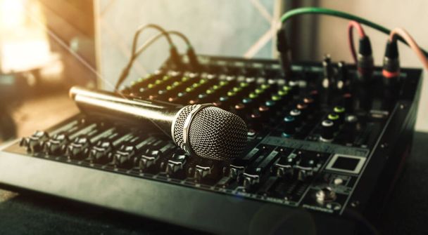 Κοντινό μικρόφωνο και μίξερ ήχου στο studio για ηχοσύστημα και ηχητικό εξοπλισμό και μουσικό όργανο. δυναμικό μικρόφωνο υψηλής ποιότητας συνδεδεμένο με αρσενικό xlr connector. - Φωτογραφία, εικόνα