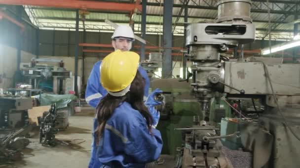 Two industrial workers in protective and safety uniforms and hardhats, male manager, and Black colleague work with metalwork machines in manufacturing factory. Professional production engineer team. - Footage, Video