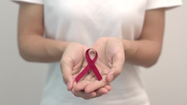 Ruční držení červené stuhy na prosinec World Aids Day, mnohočetný myelom Cancer Awareness měsíc a National Red stuha týden. Zdravotní péče a koncepce Světového dne rakoviny - Záběry, video