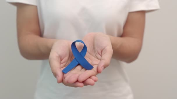 Március Colorectal Rák Tudatosság hónap, Nő kezében sötét Blue Ribbon támogató emberek életét és betegségét. Egészségügyi ellátás, remény és a rák világnapja koncepció - Felvétel, videó