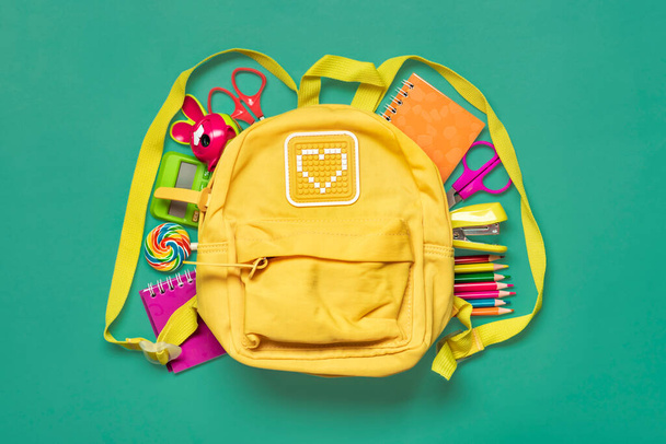 Retour à l'école, concept éducatif Sac à dos jaune avec fournitures scolaires - bloc-notes, stylos, gomme arc-en-ciel, numéros isolés sur fond vert. - Photo, image