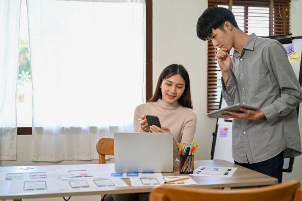 Szakmai Y-generációs ázsiai férfi és női fejlesztők dolgoznak együtt az új mobil alkalmazás prototípusán. UI UX vállalkozás indítási koncepciója - Fotó, kép
