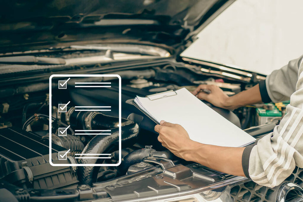 Automekaanikko tarkistaa auton moottorin tarkastamalla kirjallisesti leikepöydälle tarkistuslistan korjaus kone, auton huolto ja huolto. - Valokuva, kuva