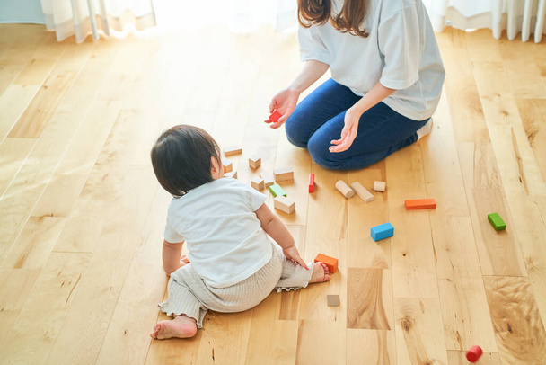 母親と子供が部屋の中でブロックを構築して遊ぶ - 写真・画像